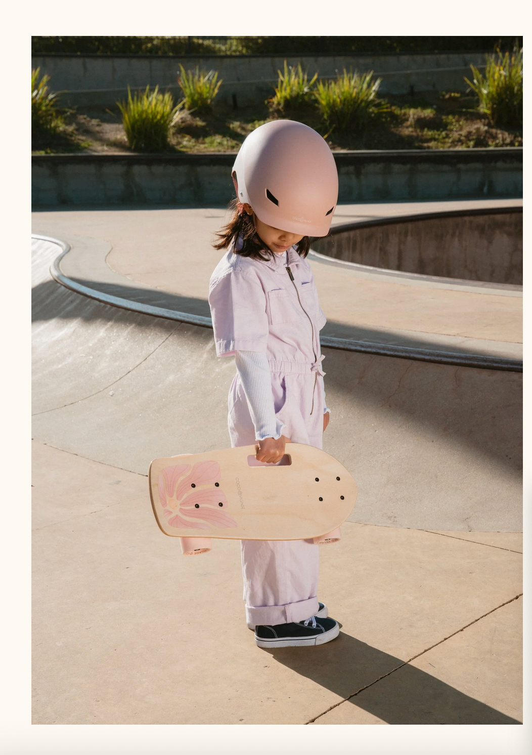 Child holding a skateboard at a skate park