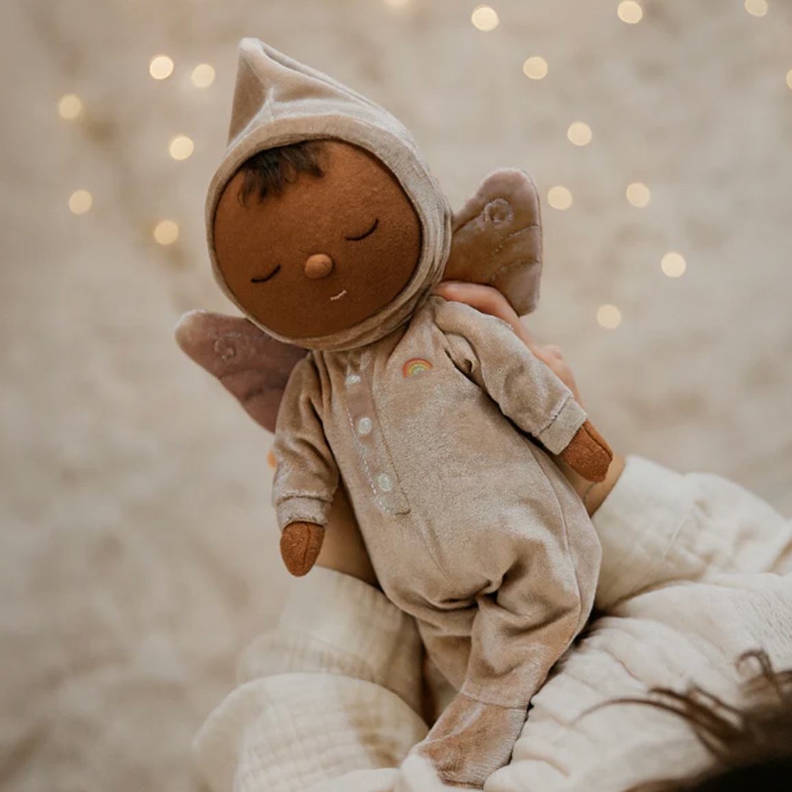 Baby doll in a beige outfit with animal ears against a soft, blurred background