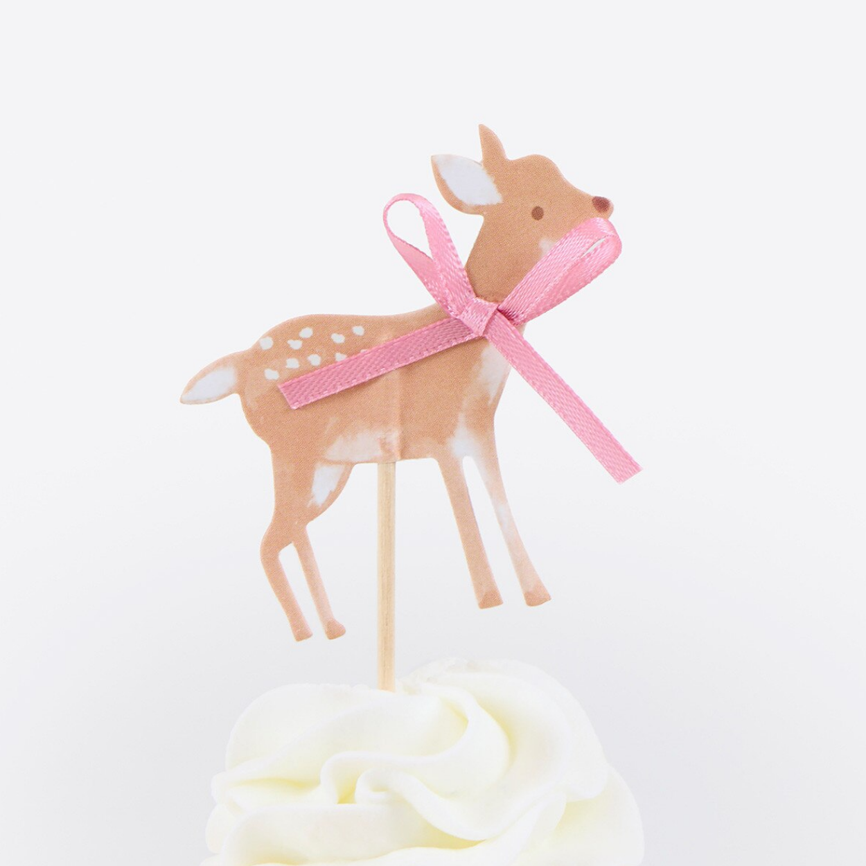 Deer-shaped cake topper with a pink ribbon on a white background