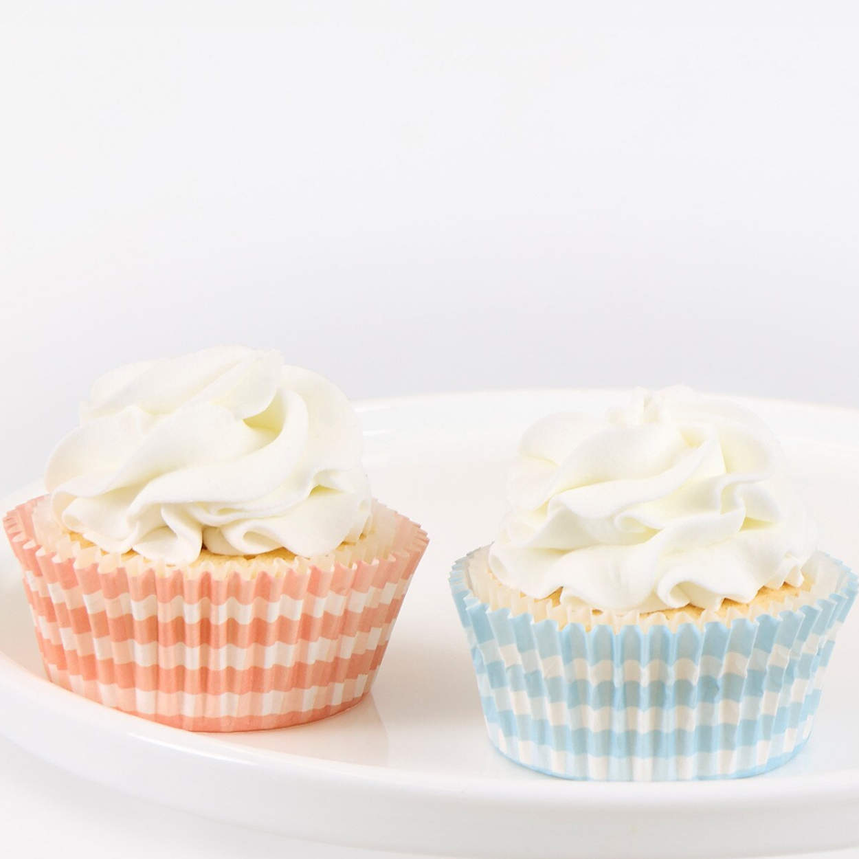 Two cupcakes with white frosting on a white background