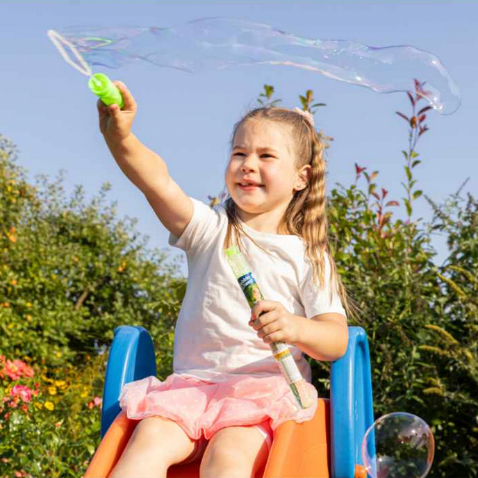 Child playing with bubble wand outdoors on a sunny day