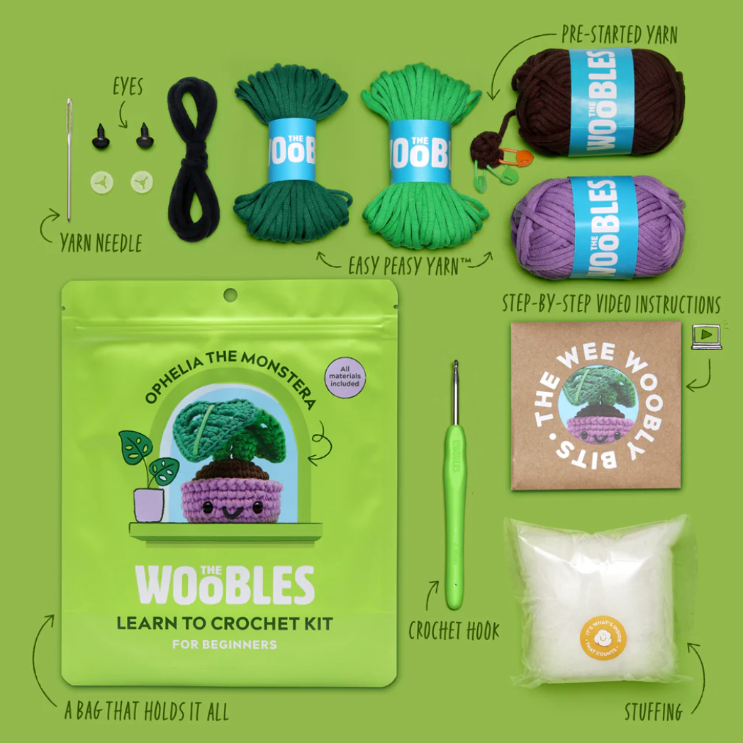 Woobles learn to crochet kit with yarn, hook, and other supplies on a green background