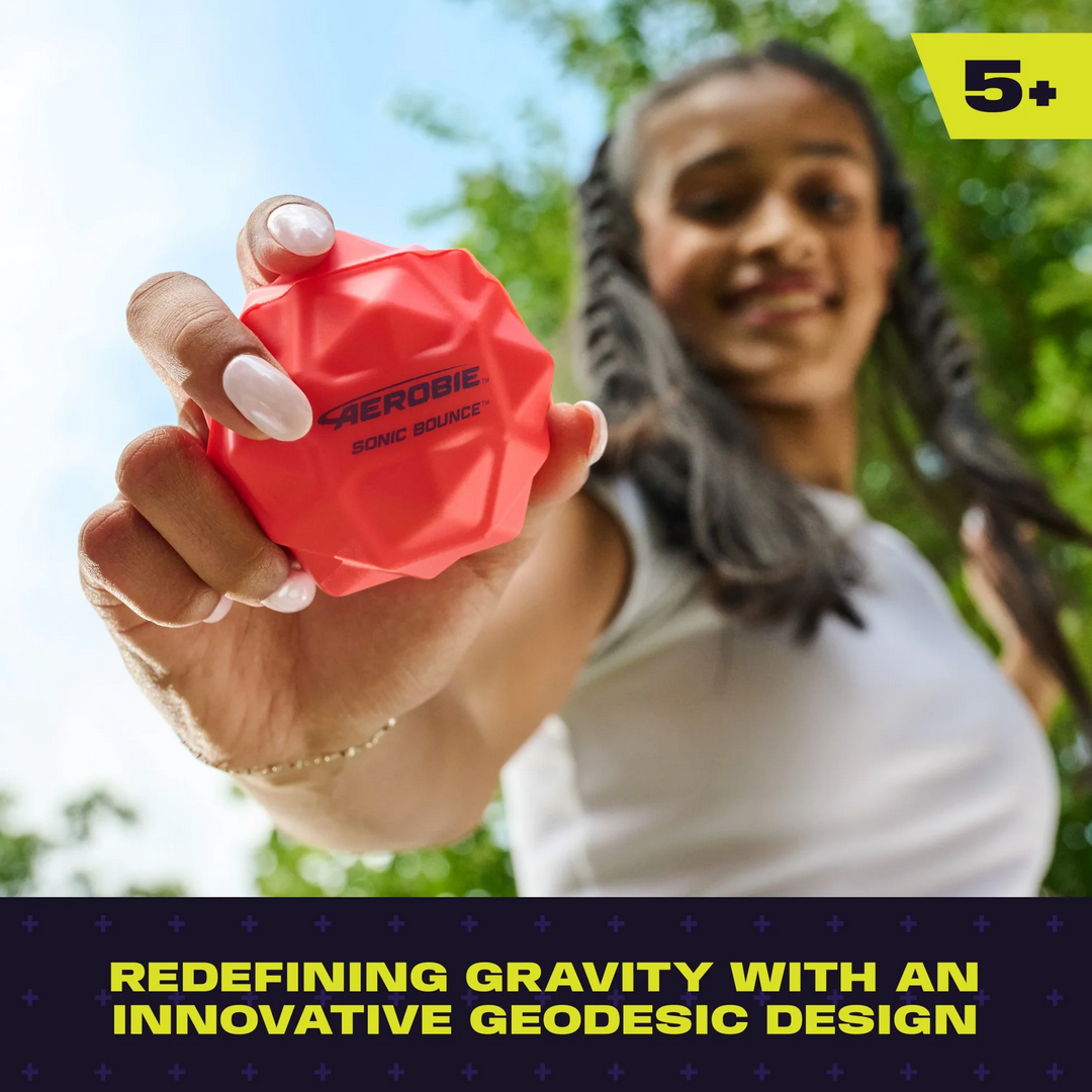 Person holding a red ball with text about geodesic design outdoors
