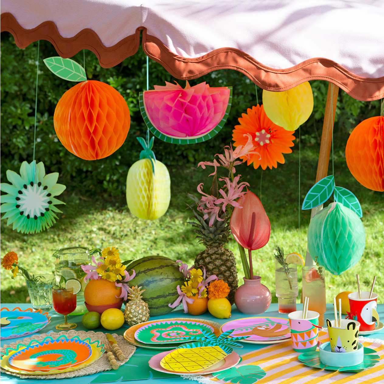 Colorful outdoor party setup with decorations and tableware on a grassy background