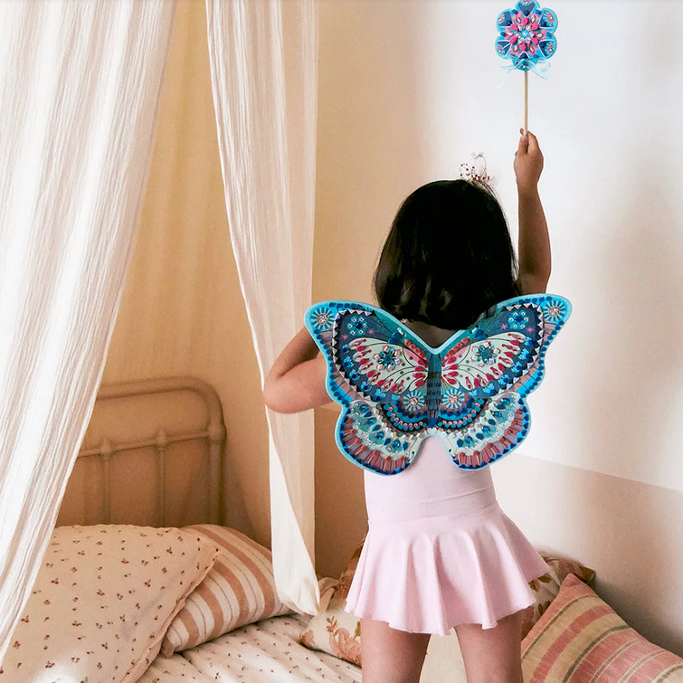 Child wearing a colorful butterfly costume in a bedroom setting