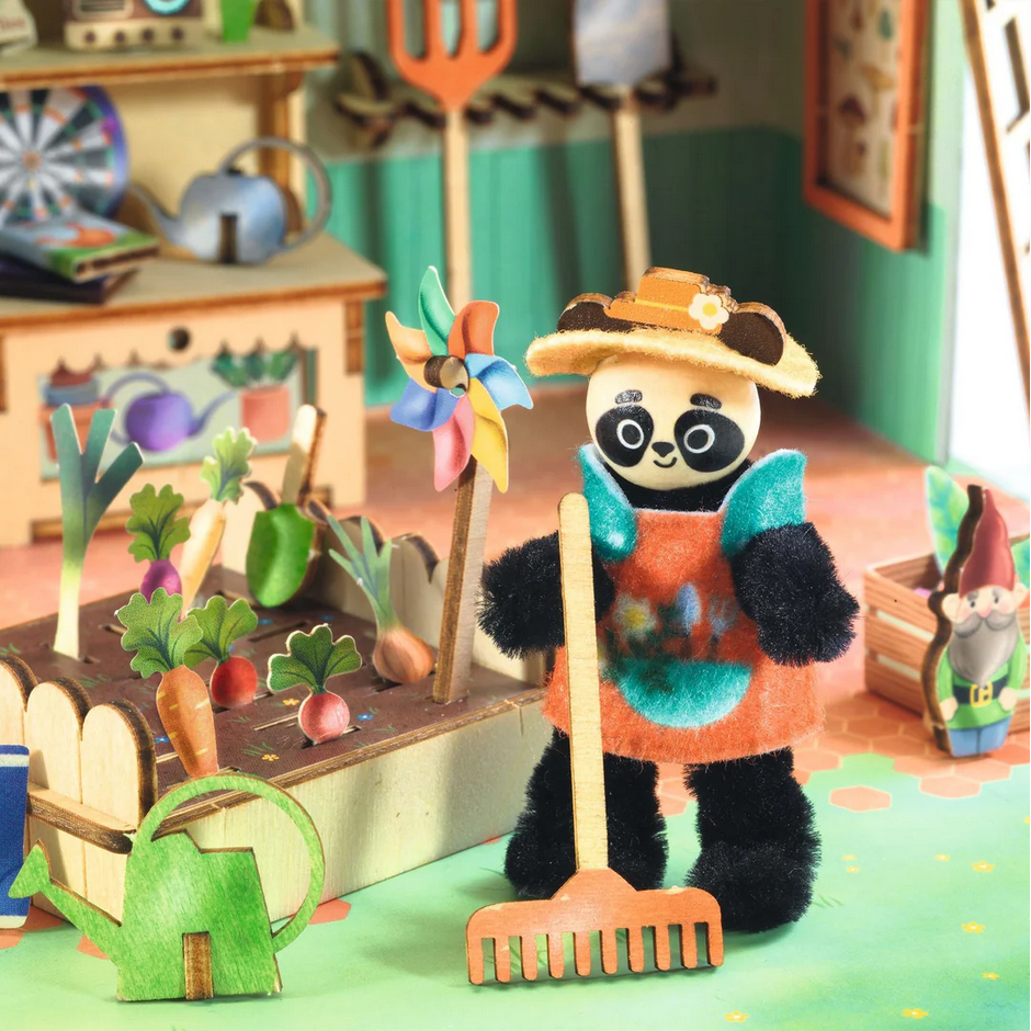 Toy panda in a garden setting with gardening tools and plants