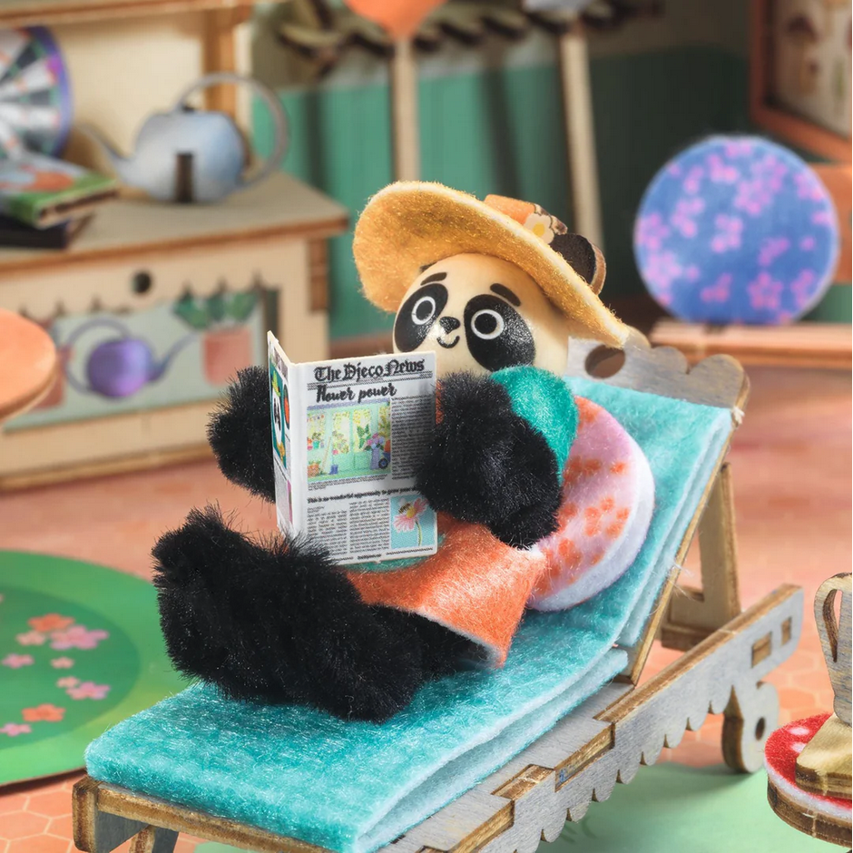 Panda toy reading a newspaper on a deck chair in a colorful room setting