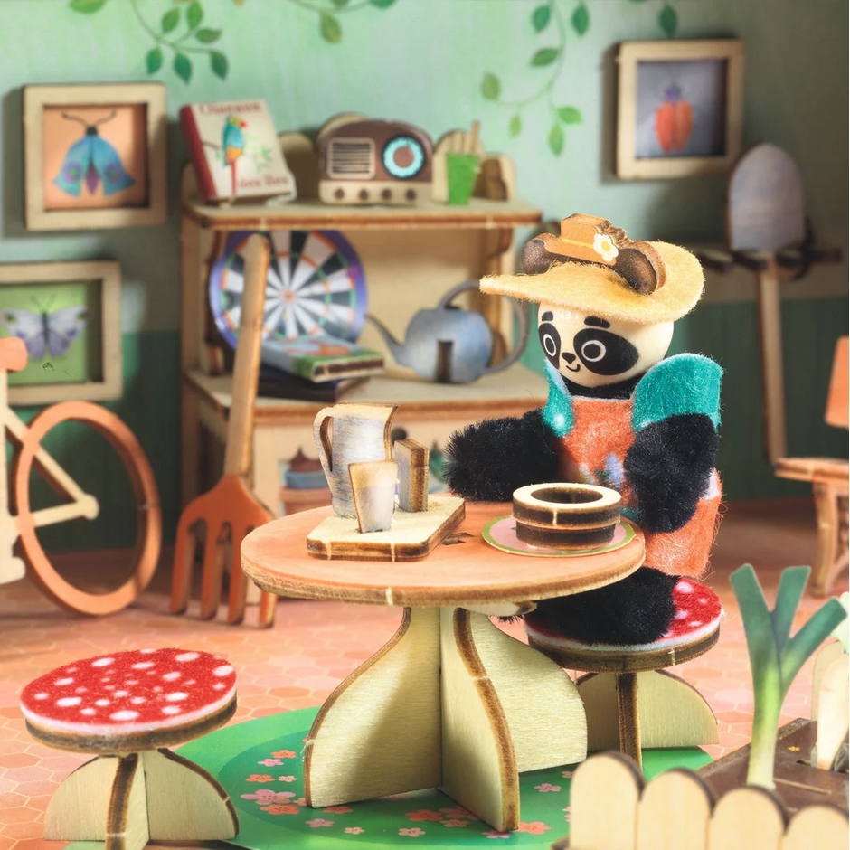 Miniature panda character sitting at a table in a cozy room with decorative elements.