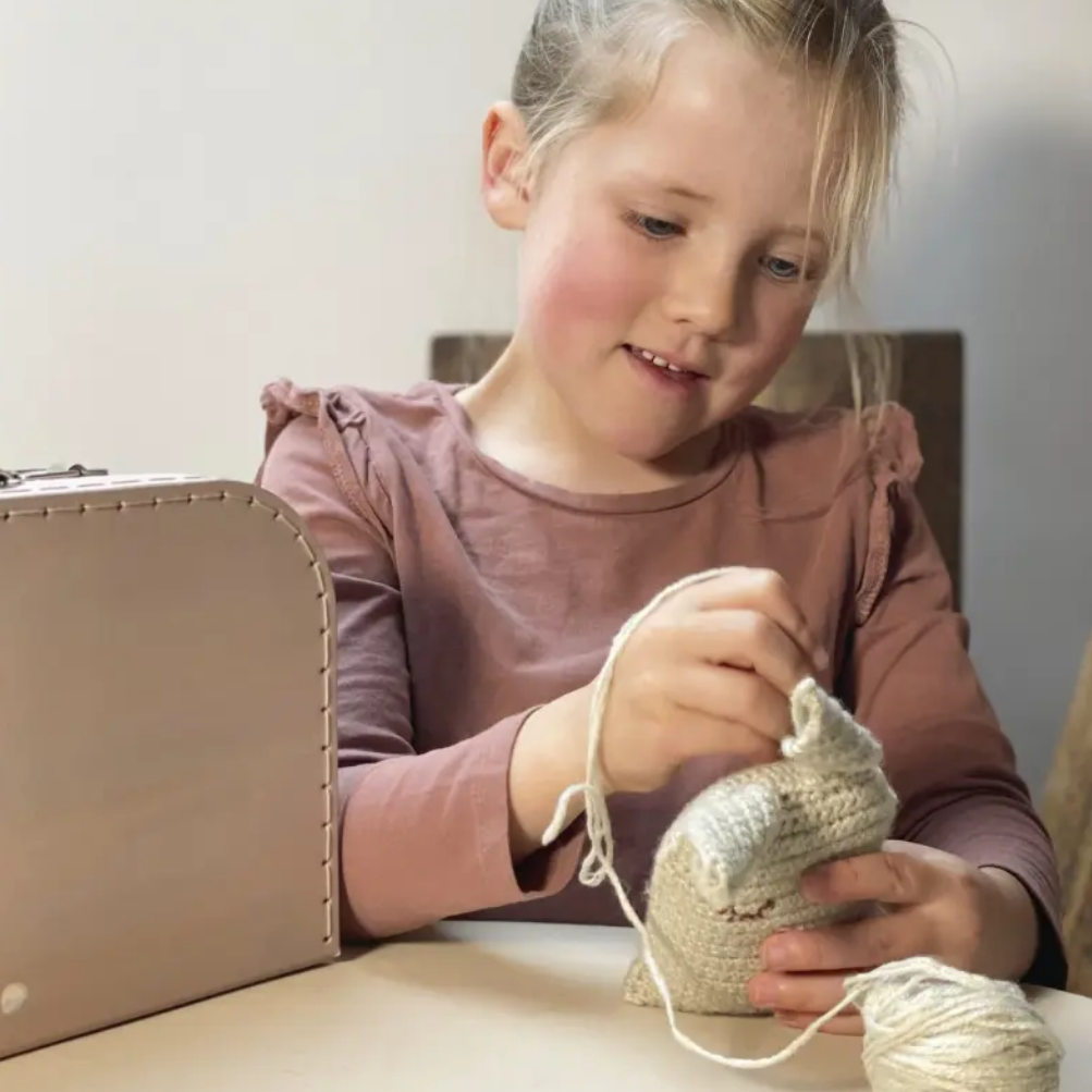 Young girl knitting with yarn on a table