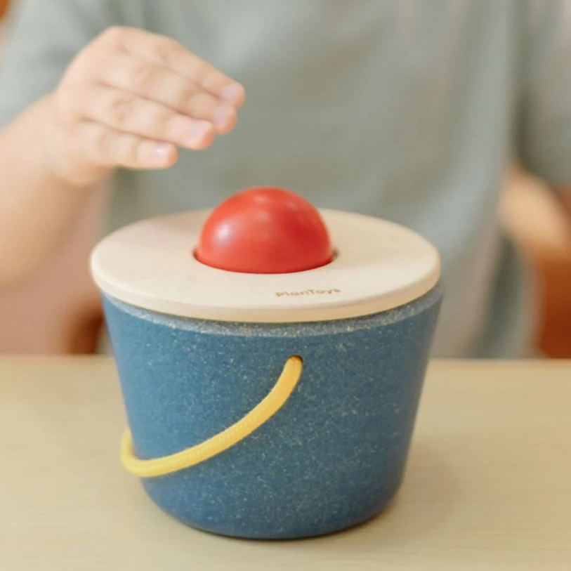 Children's wooden toy with a red ball on top, placed on a table.