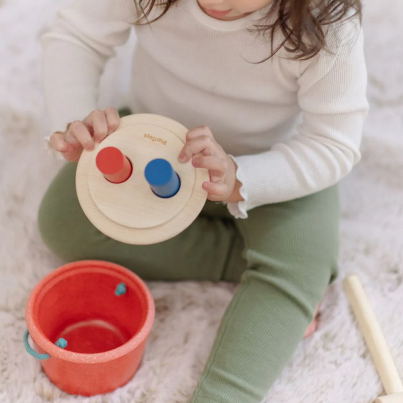 Child playing with a wooden toy on a soft surface