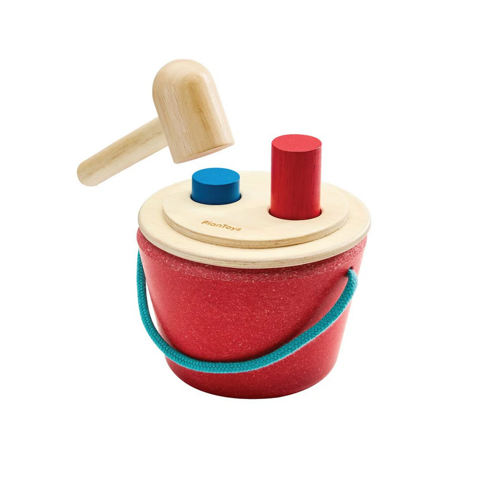 Wooden toy with a red bucket, blue and red shapes, and a hammer on a white background.