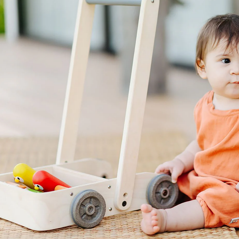 Child playing with a wooden toy cart outdoors