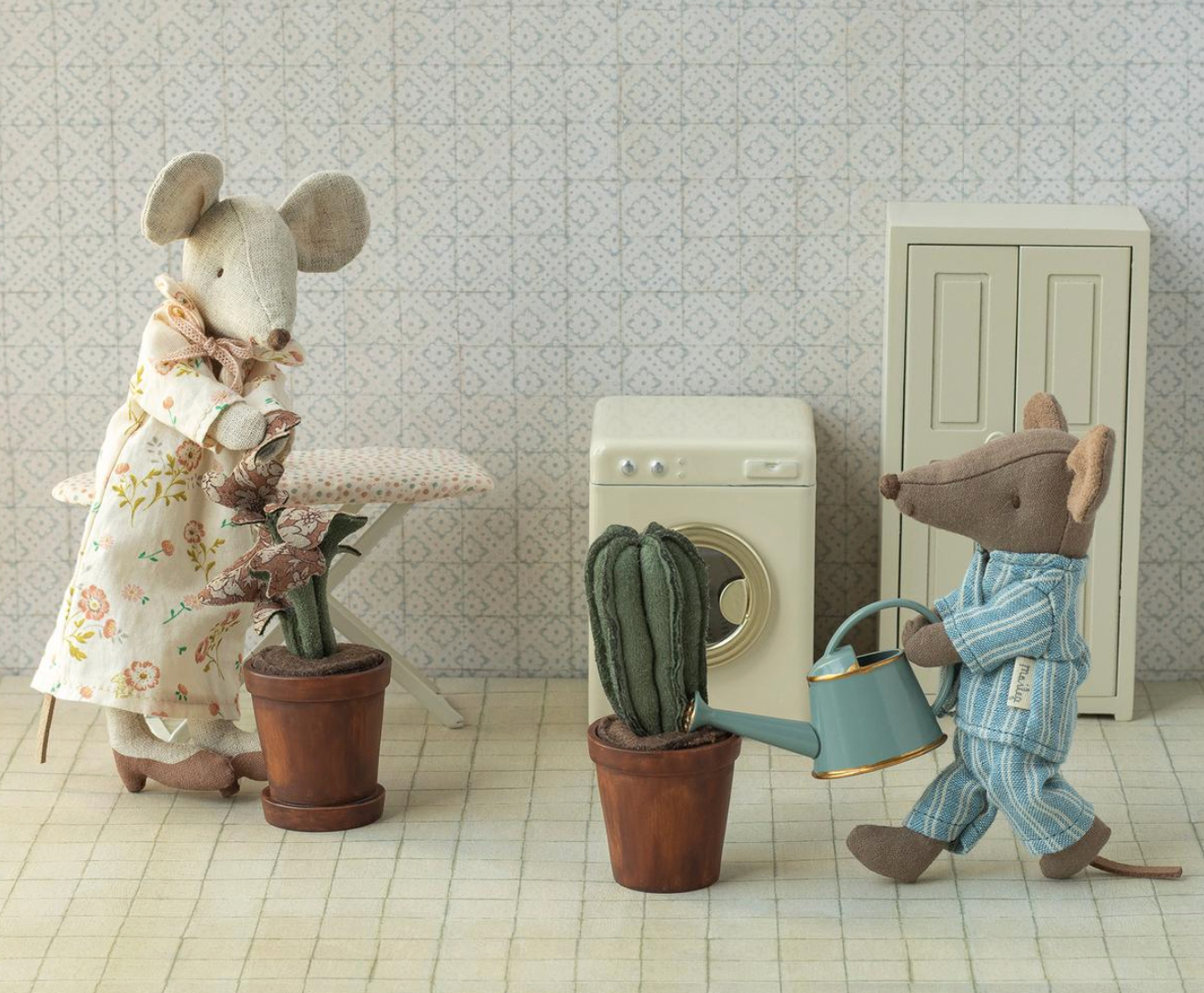 Two toy mice in a room with a washing machine and potted plants.