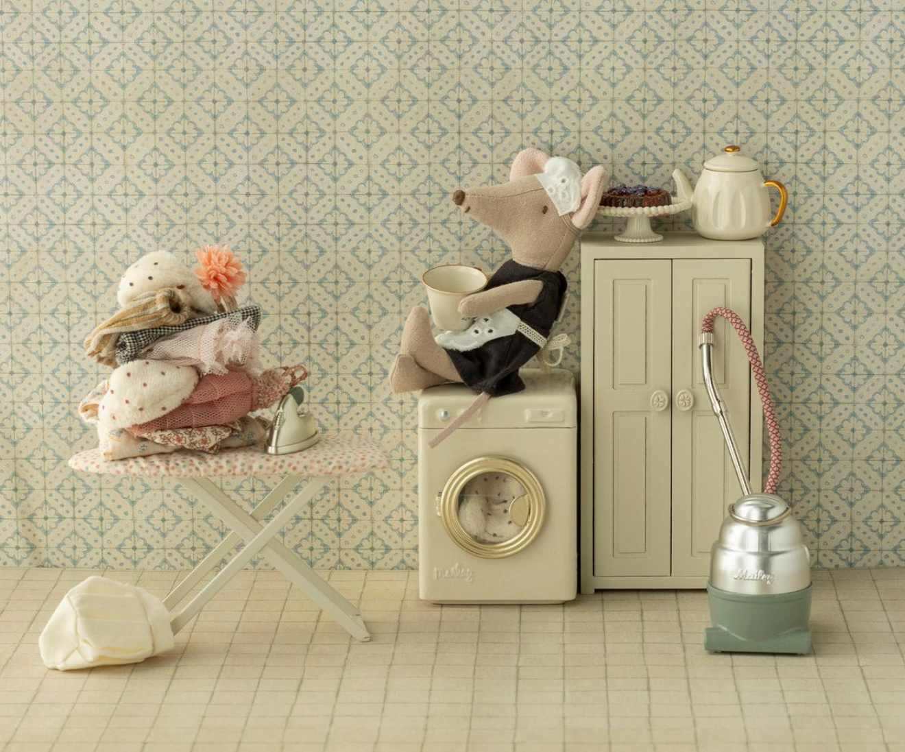 Miniature scene with stuffed animals in a kitchen setting on a patterned wallpaper background