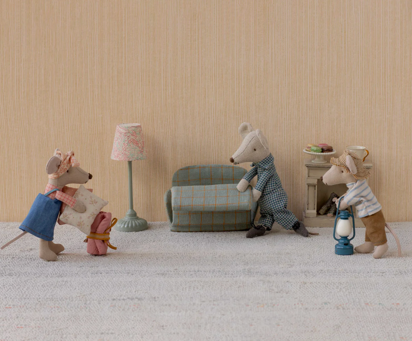 Toy mouse family in a living room setting with a lamp, sofa, and coffee table.