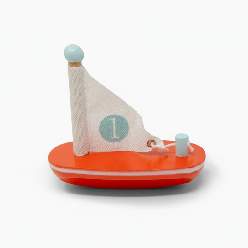 Toy sailboat with a red base and white sail on a white background