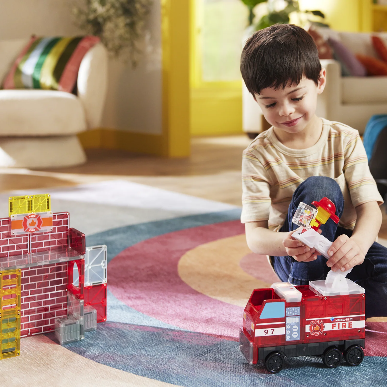 Child playing with a toy fire truck on a colorful rug in a living room.