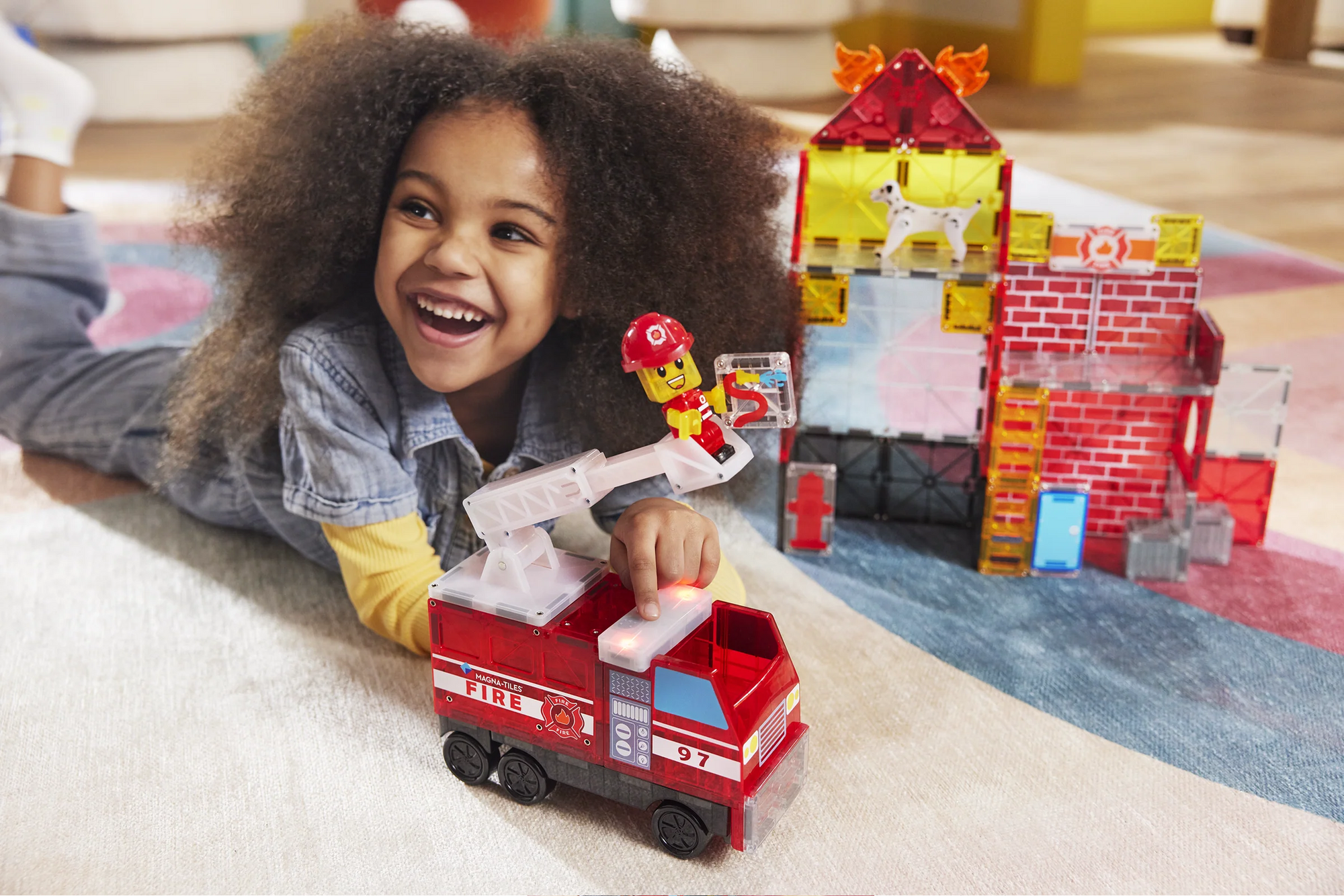 Child playing with a toy fire truck and building set on a carpeted floor.