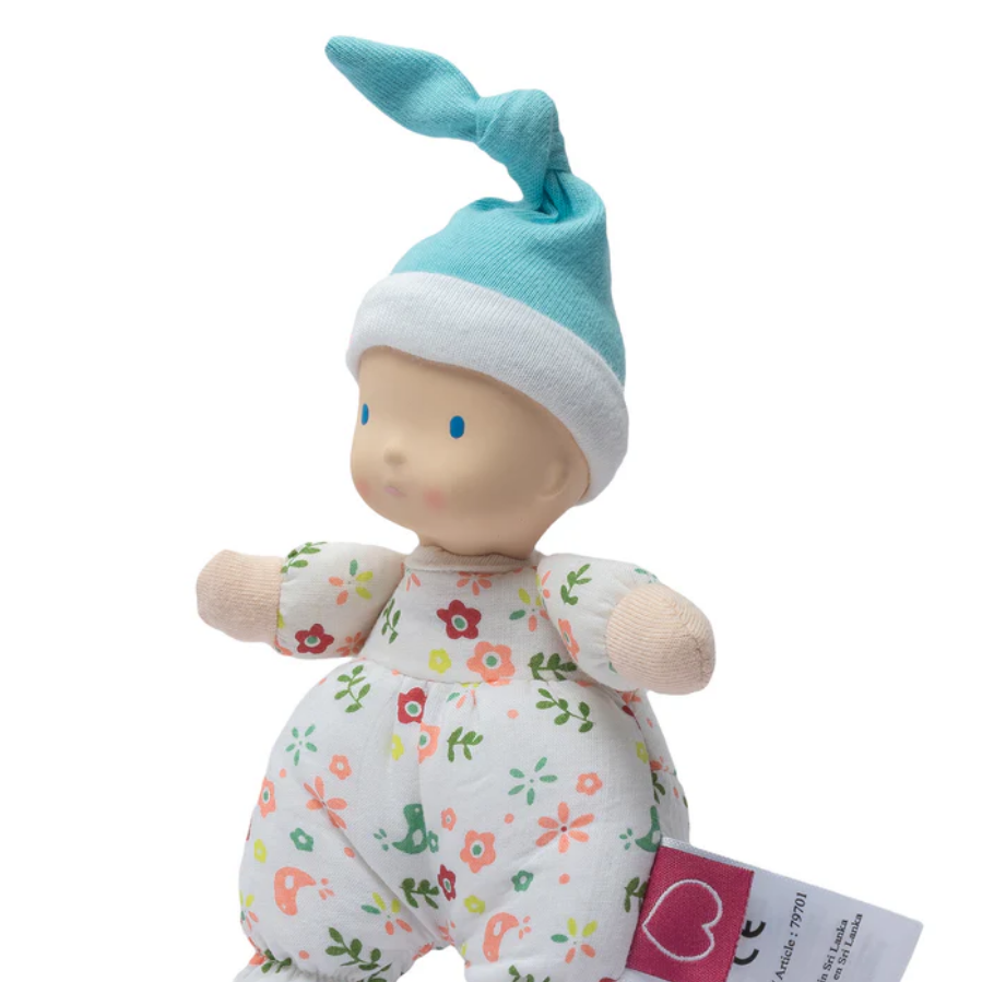 Baby doll with floral onesie and blue hat on a white background