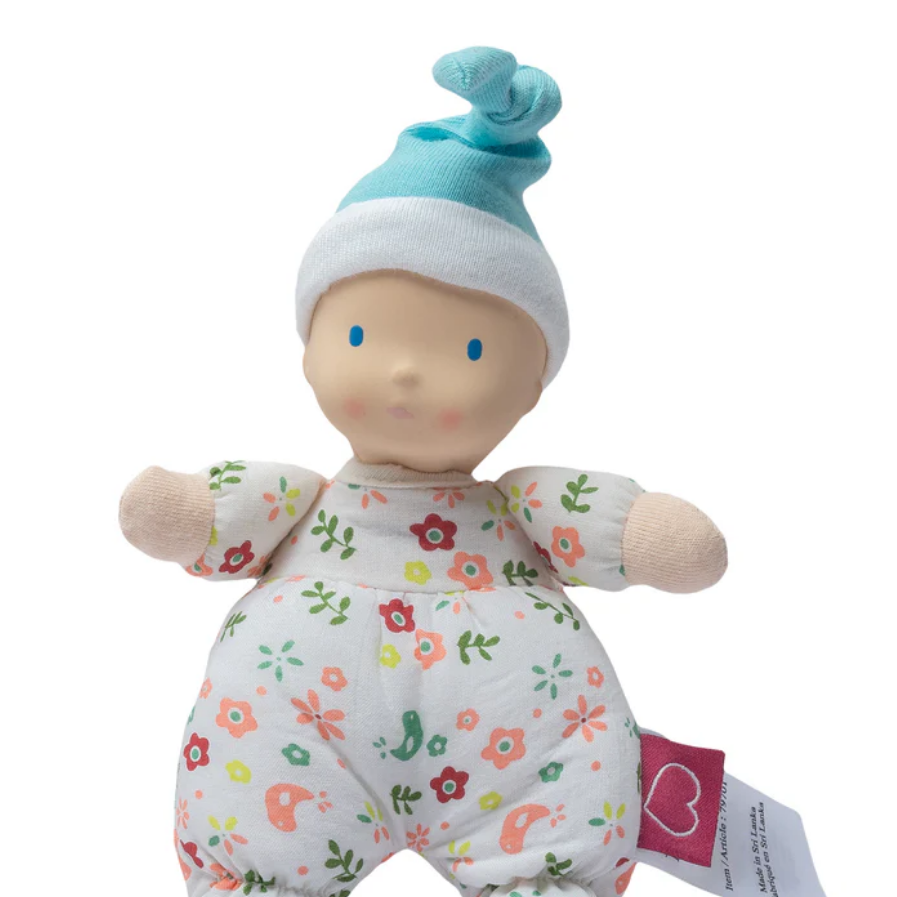 Baby doll with floral patterned outfit and blue hat on a white background