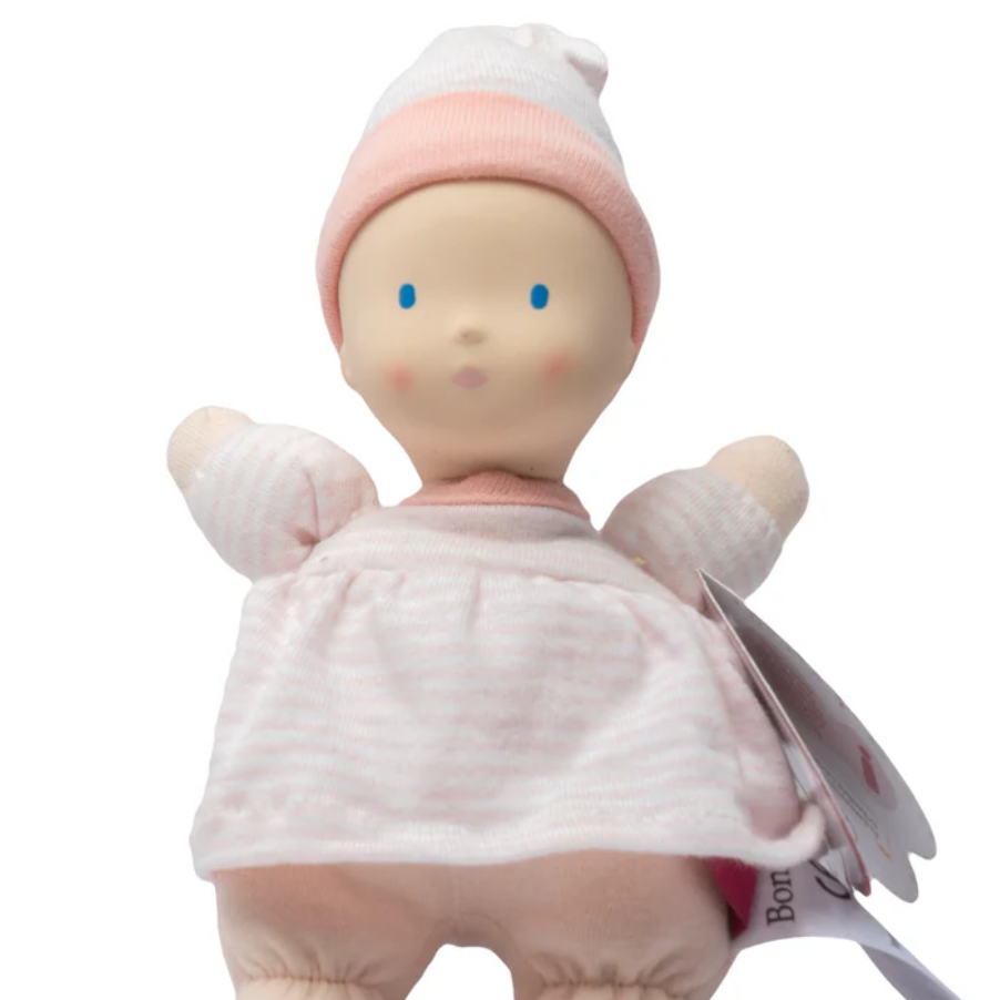 Baby doll in pink outfit with a white background