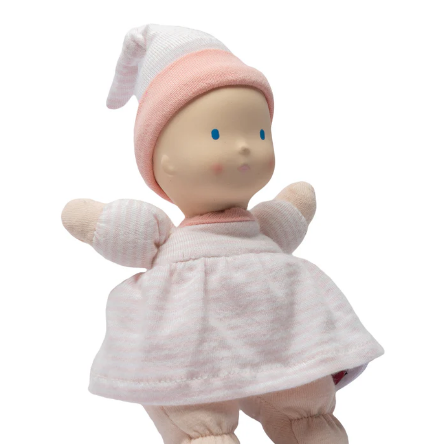 Baby doll in pink outfit with matching hat on a white background