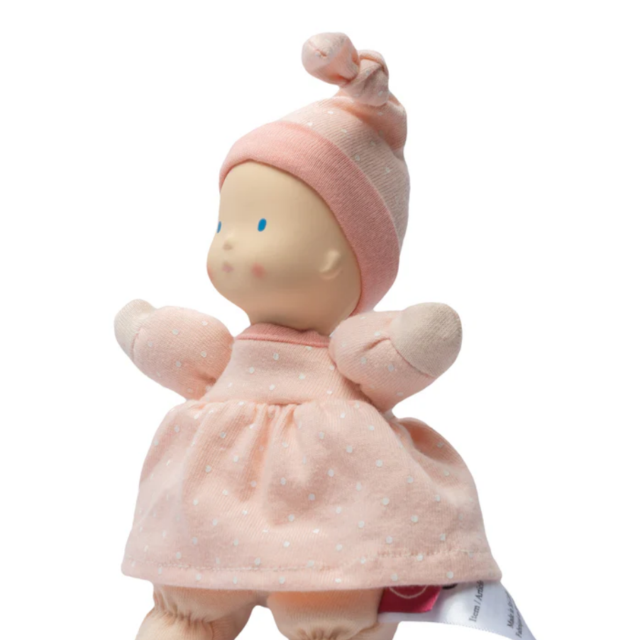 Stuffed doll in a pink outfit with a matching hat on a white background