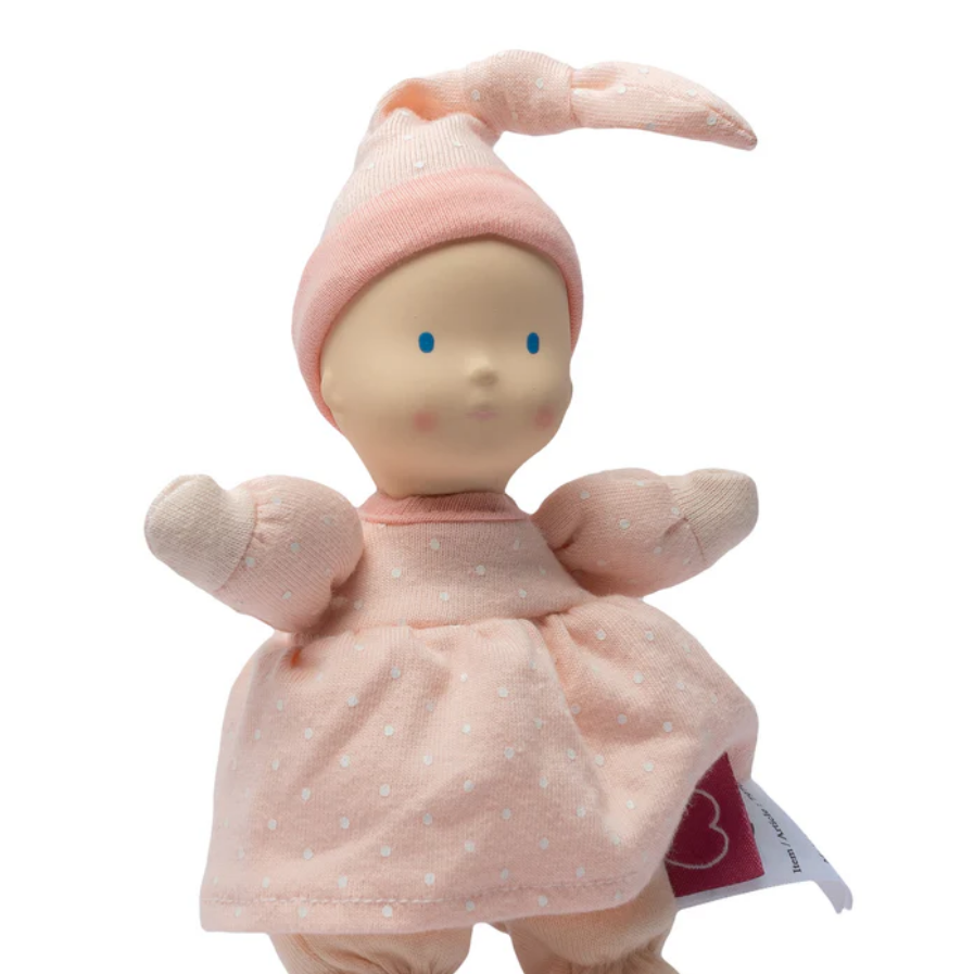 Plush baby doll in a pink outfit with a matching hat on a white background