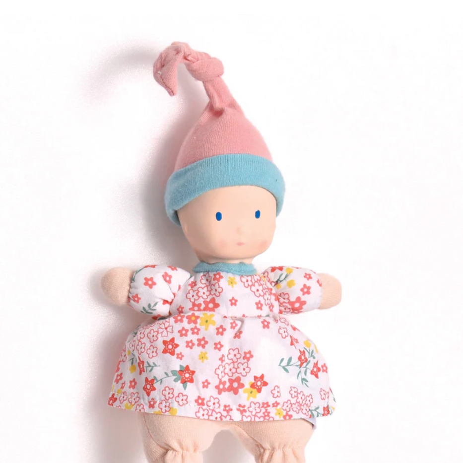 Toy doll with floral outfit and colorful hat on a white background