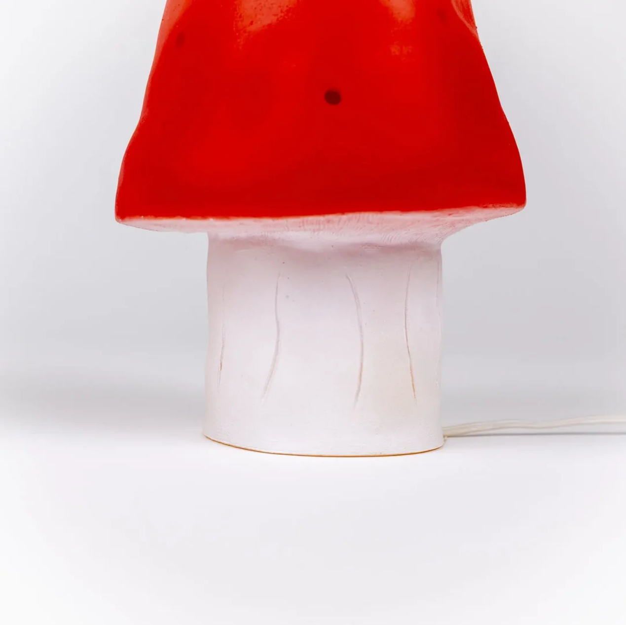 Mushroom-shaped object with a red cap and white stem on a white background