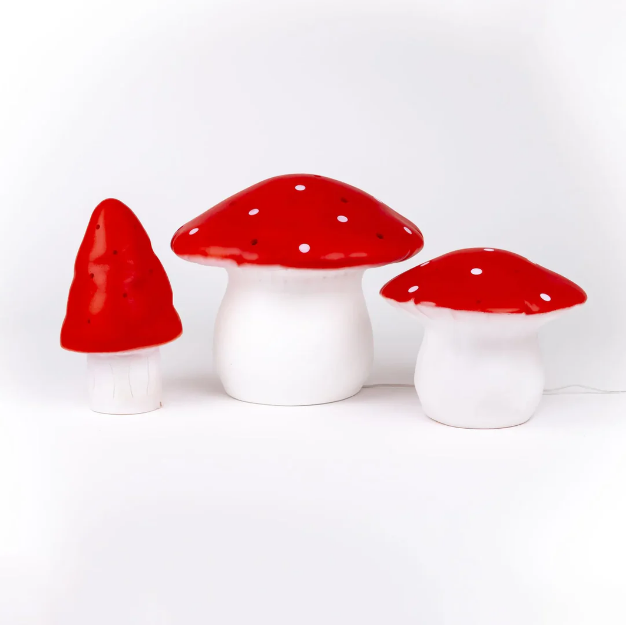 Three mushrooms with red caps and white stems on a white background