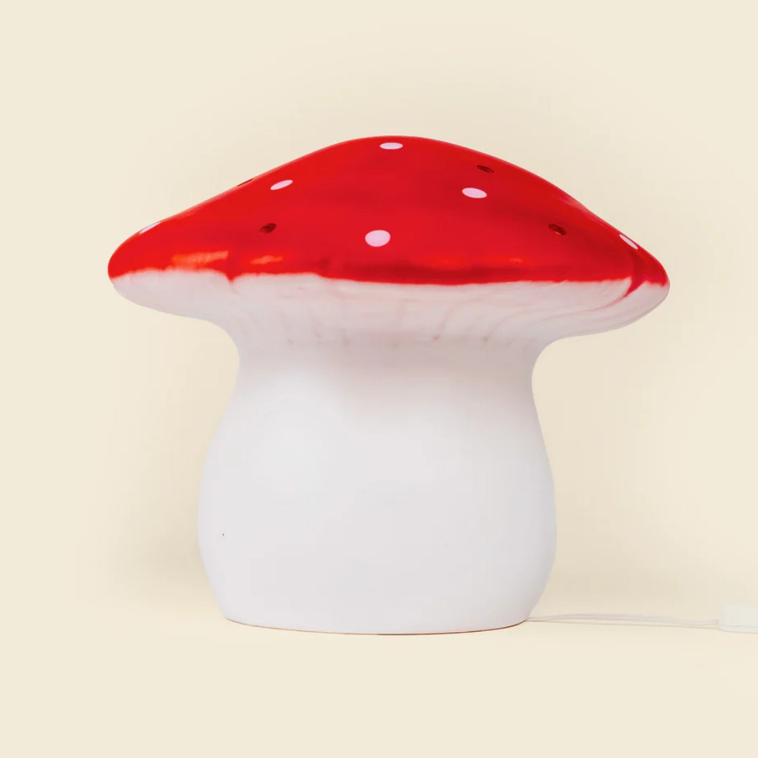 Mushroom-shaped lamp with red cap and white stem on a beige background