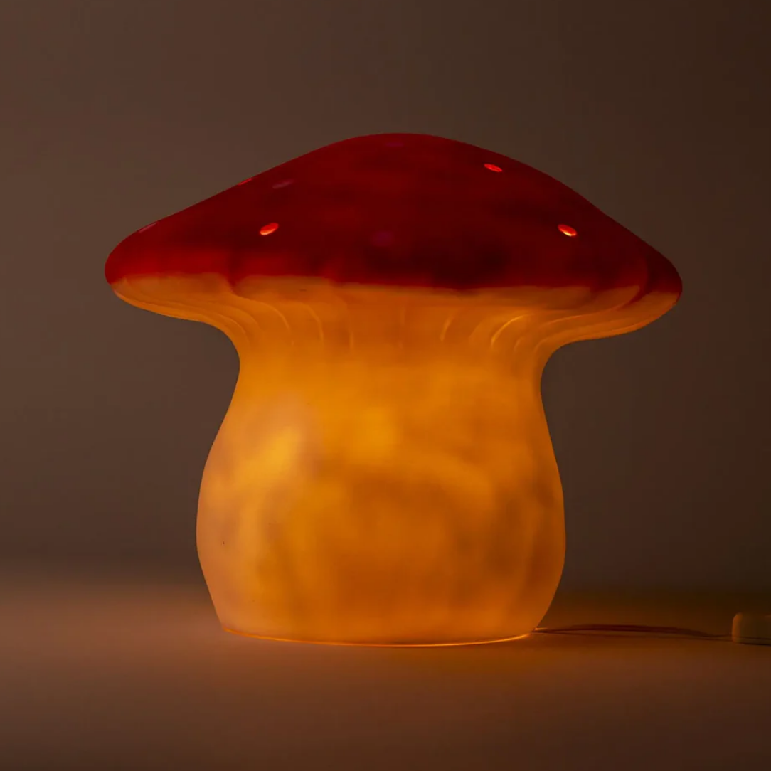 Mushroom-shaped lamp with a red cap and orange body on a dark background