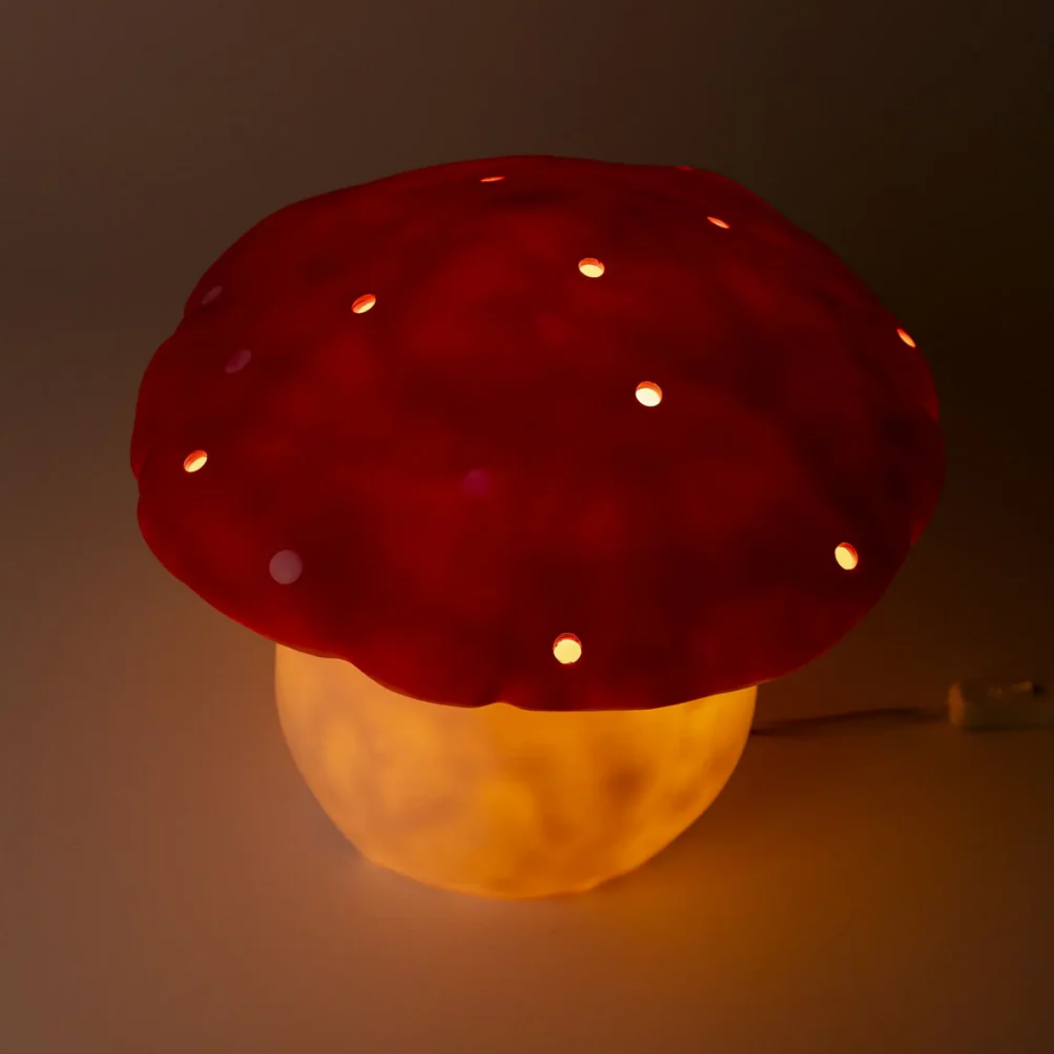 Mushroom-shaped night light with red cap and yellow base on a dark background