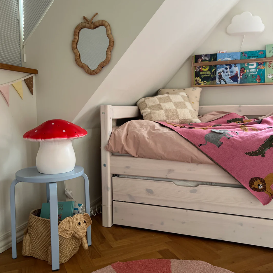 Children's bedroom with a bed, mushroom-shaped lamp, and colorful rug.