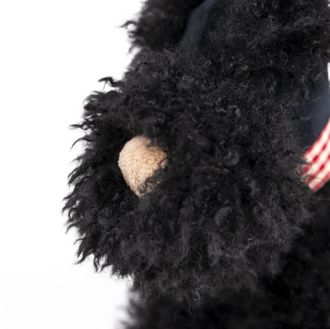 Close-up of a black plush toy with a textured paw on a white background