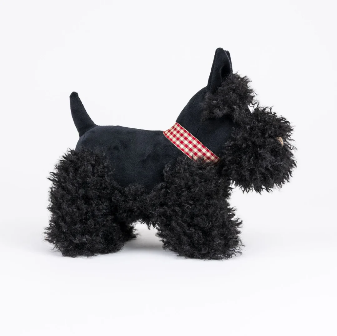 Black stuffed dog toy with a red checkered collar on a white background