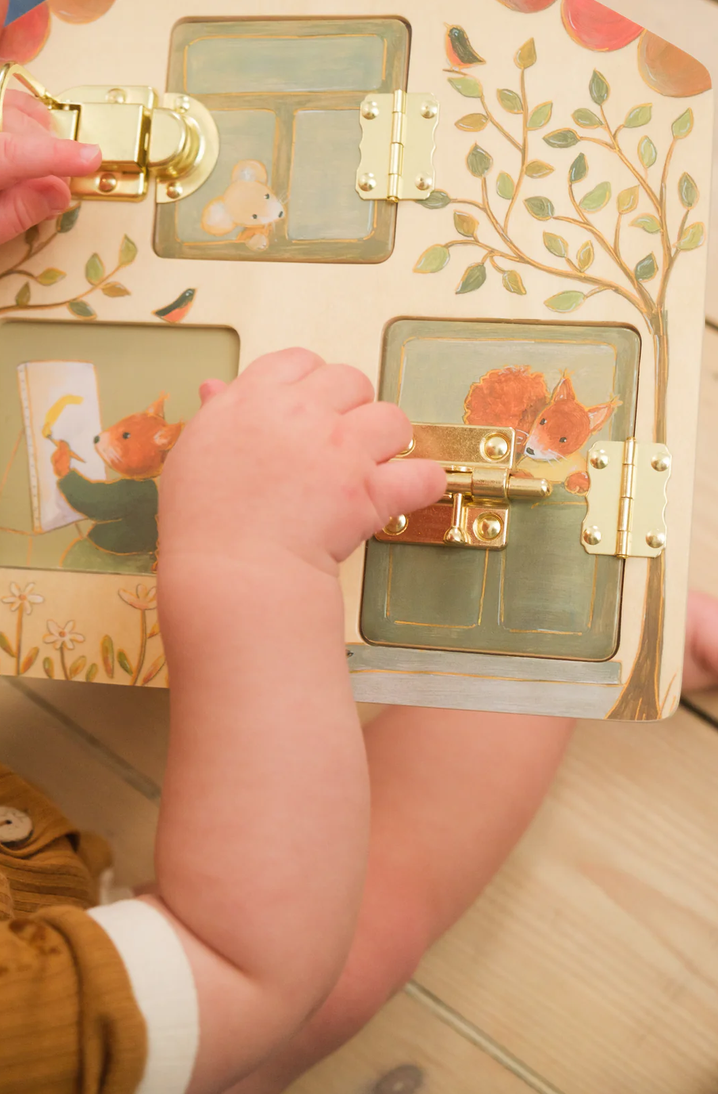 Child's hand interacting with a wooden toy chest featuring animal illustrations.