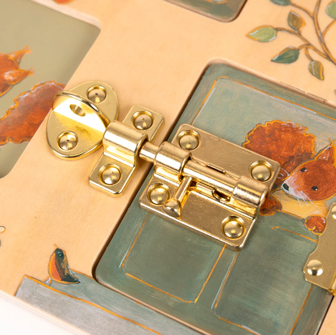 Close-up of a gold latch on a decorative box with fox illustrations.