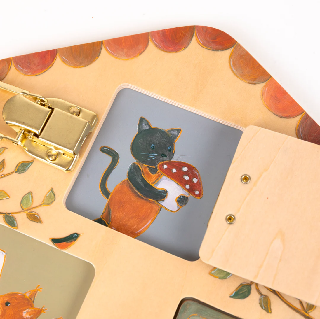 Close-up of a handbag with a cat and mushroom design on a flap.