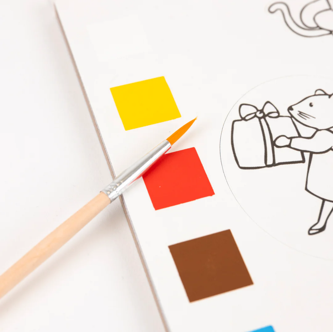 Color swatches with a paintbrush and a black and white illustration of a cat holding a gift.