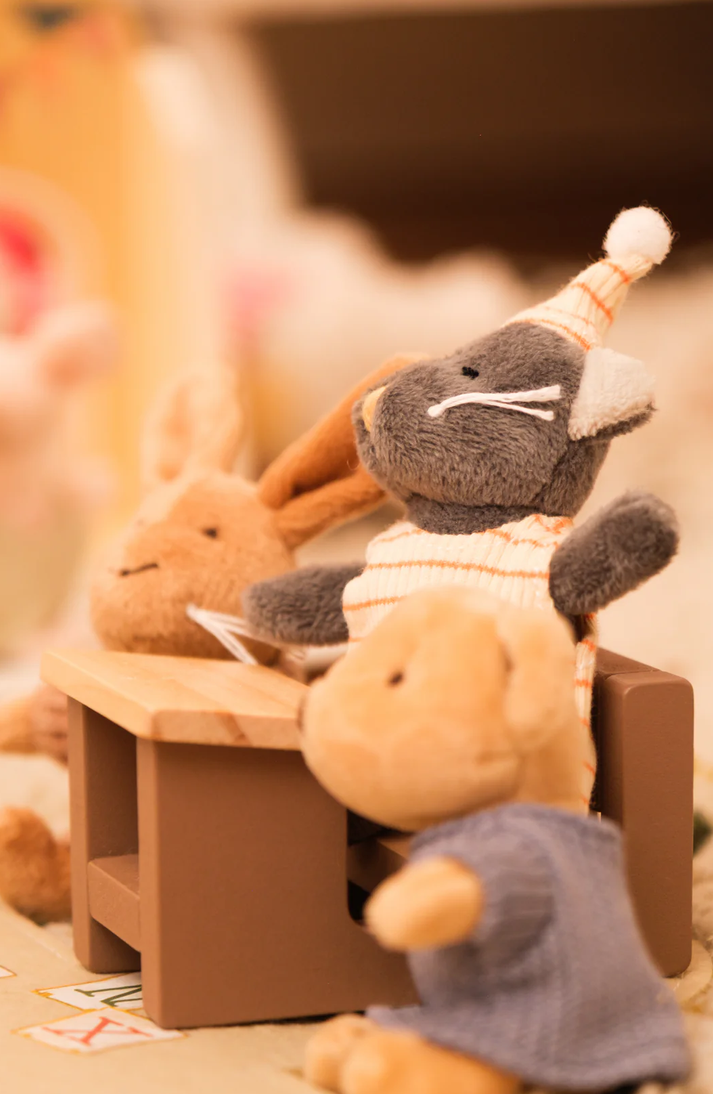 Plush toys resembling a cat and rabbit sitting on a small wooden bench.