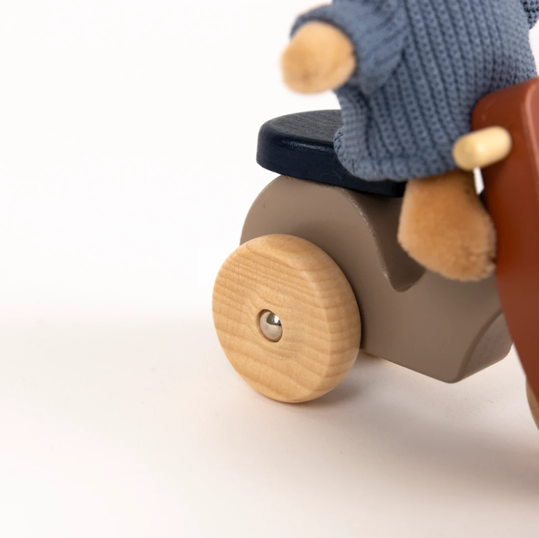 Wooden toy scooter with a small figure wearing a blue sweater on a white background