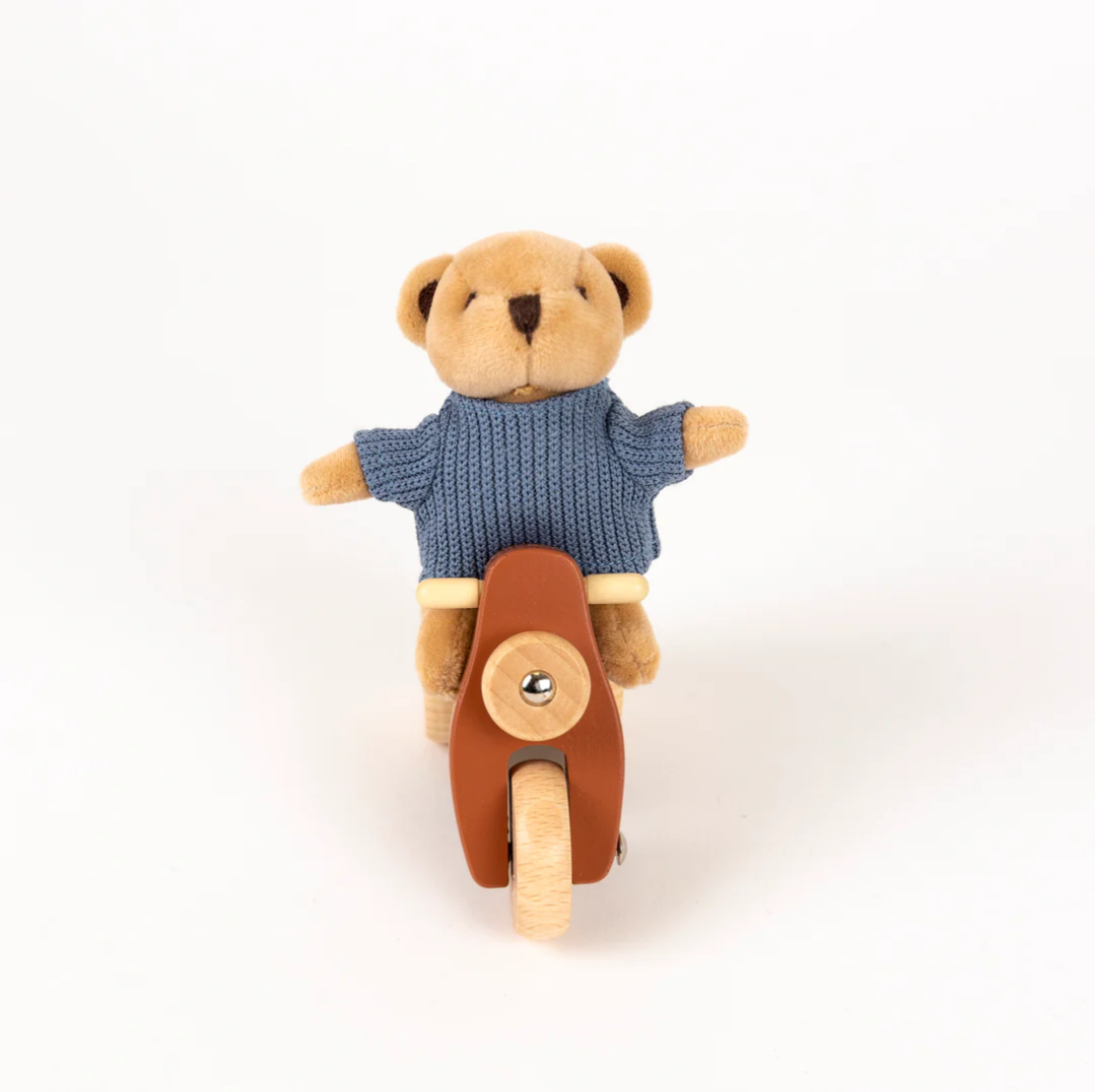 Teddy bear in a blue sweater riding a brown scooter on a white background