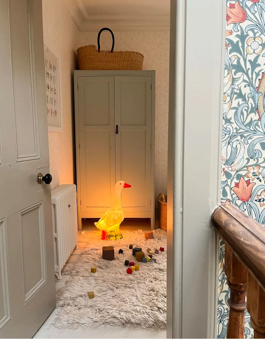 Children's room with toys on the floor, a wardrobe, and floral wallpaper.