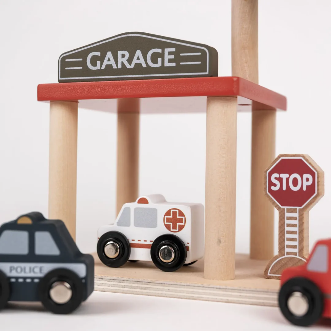 Wooden toy garage with toy cars and a stop sign on a white background