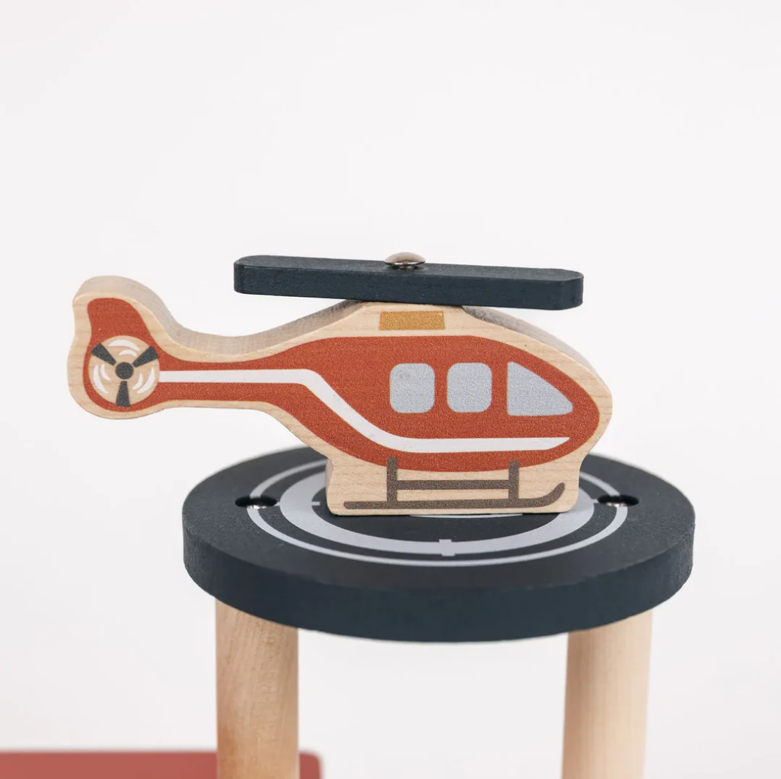 Wooden helicopter toy on a black platform with a white background