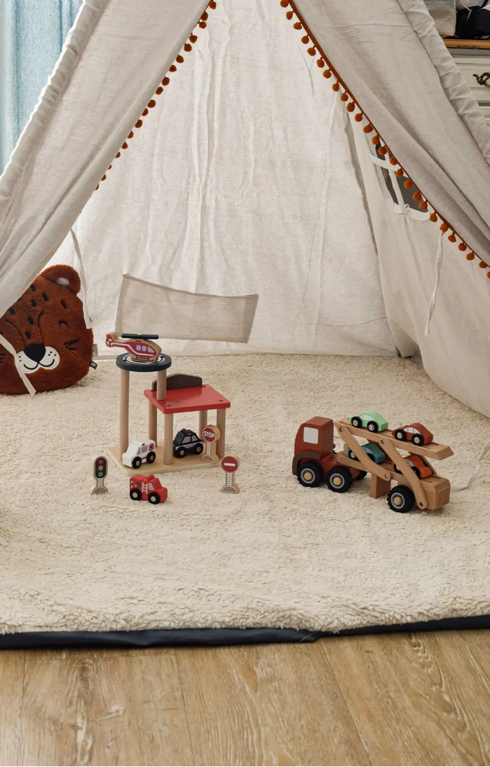 Children's play area with a teepee, toys, and a rug on a wooden floor.