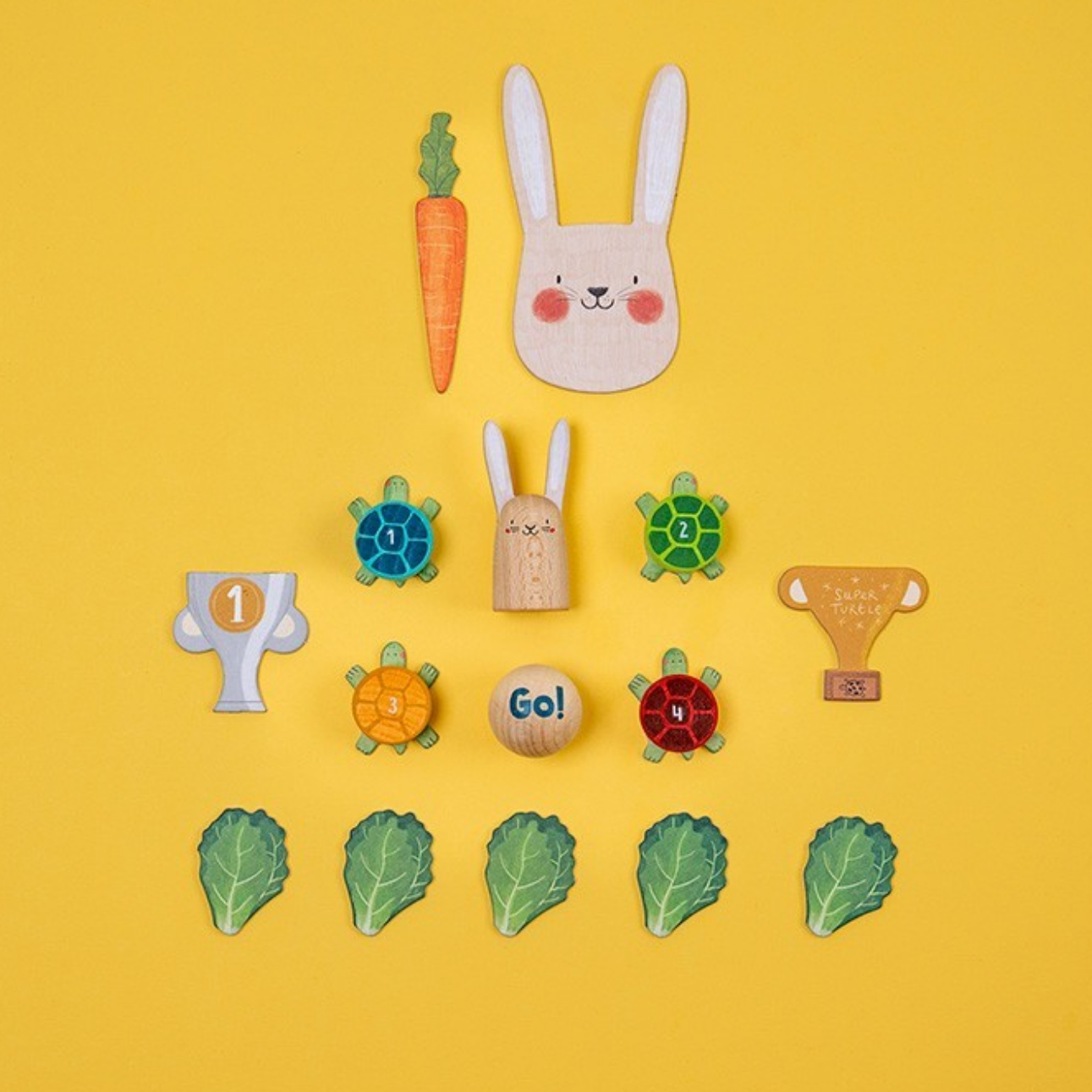 Collection of wooden toys including a rabbit, carrot, turtles, and leaves on a yellow background.